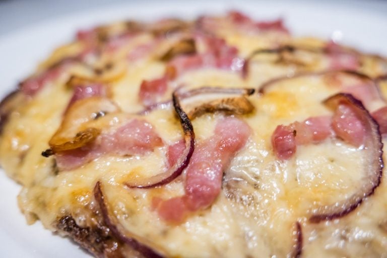 A Meatza Recipe Topped With Bacon And Cheese