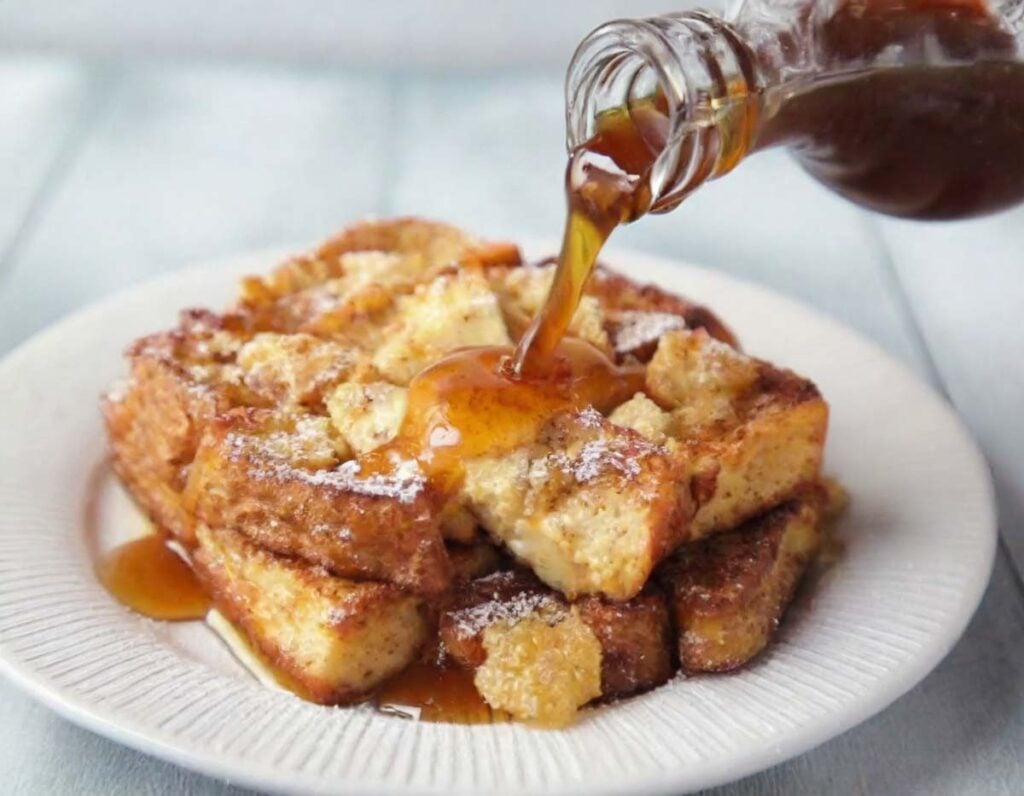 pouring maple syrup on the Creamy Vanilla French Toast Casserole